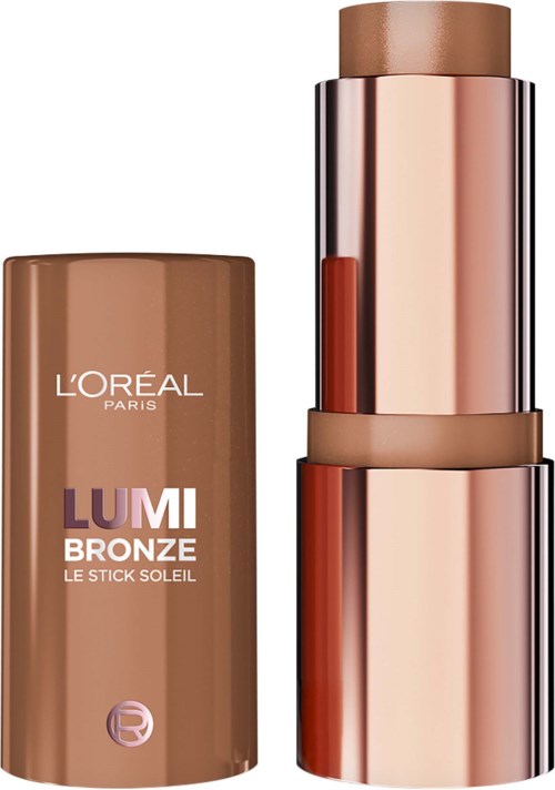 A bronze stick makeup product with a matching case and a shiny, metallic outer cover. The cap is placed beside the product.