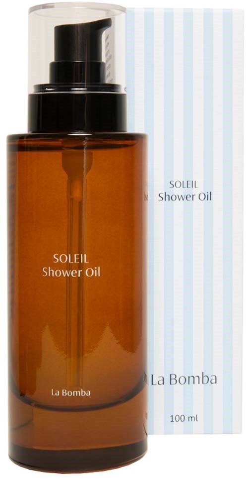 Gulbrun flaske med Soleil Shower Oil med svart pumpe og lys blå stripete eske i bakgrunnen.