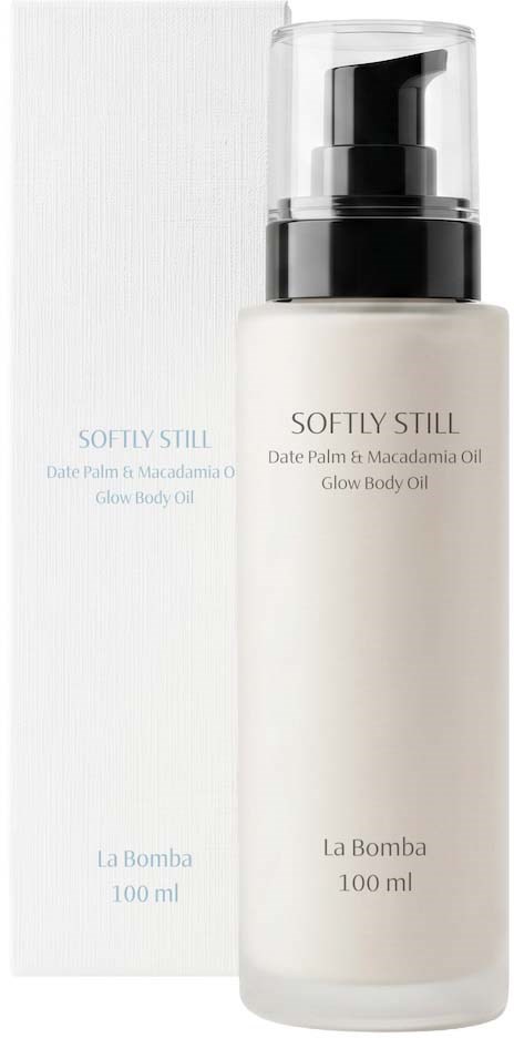 En hvit flaske med svart pumpe og gjennomsiktig lokk, merket Softly Still glow body oil fra La Bomba.