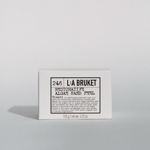 Een kleine witte doos met 'L:A BRUKET' label, bevat 120g herstellende handpeeling met vlierbloesem.