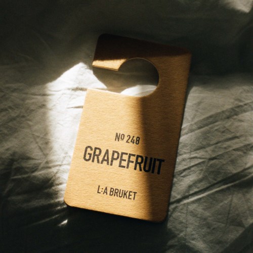 Ein Holztürhänger mit den Worten "Grapefruit" und "L:A Bruket," im Sonnenlicht.