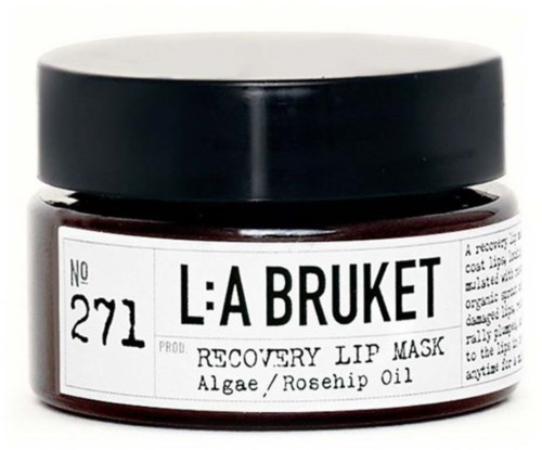 Kleiner Behälter mit Lippenmaske, schwarzer Deckel, enthält Algen und Hagebuttenöl. Beschriftet 'L:A BRUKET RECOVERY LIP MASK'.