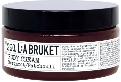 A jar of L:A Bruket body cream with bergamot and patchouli, containing nourishing ingredients for skin. The label has product details.