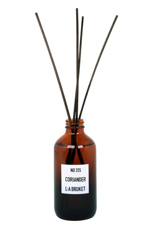 Eine braune Glasflasche mit Etikett und mehreren dünnen Stäbchen oder Diffusoren darin.