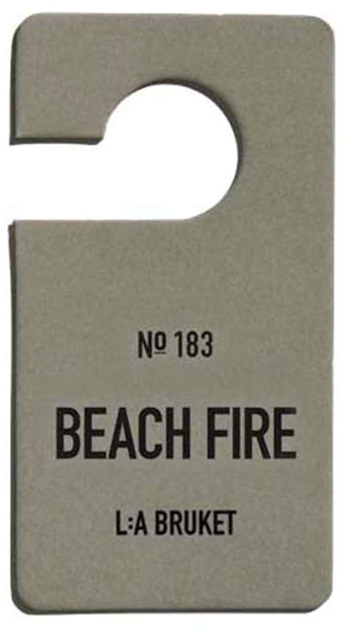 Ein graues Etikett mit Loch oben, beschriftet 'BEACH FIRE' und 'L:A BRUKET'.