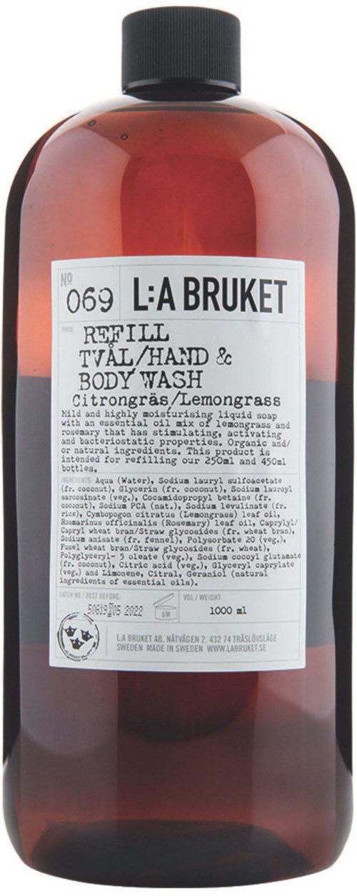 A large brown bottle with a black cap, label shows product name and description, contains liquid body wash.