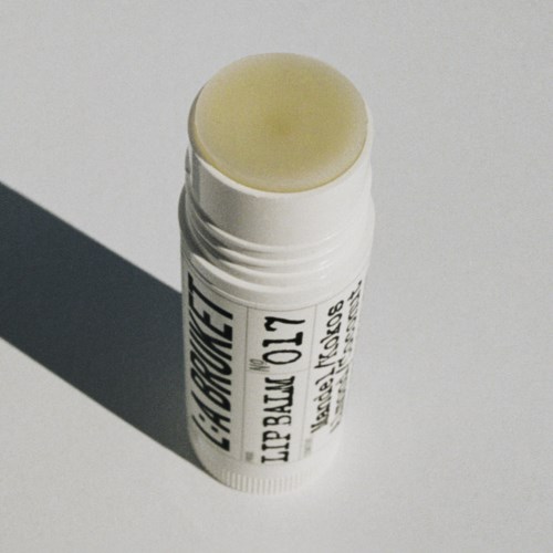 Lippenpflegestift mit gelbem Balsam auf, wirft Schatten auf den Hintergrund.