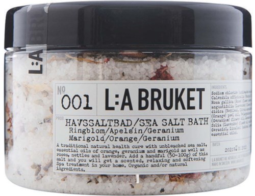 Een zeezoutbad met sinaasappel en geraniumsgeur, kleine pot met etiket met ingrediënten en naam.