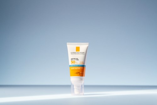 A tube of La Roche-Posay sunscreen with SPF 50 stands on a light surface against a gradient blue background.