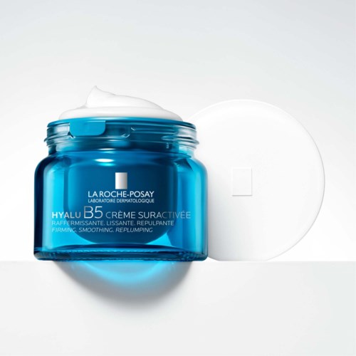 Blue jar of La Roche-Posay cream with foam on top, and a white lid beside it.