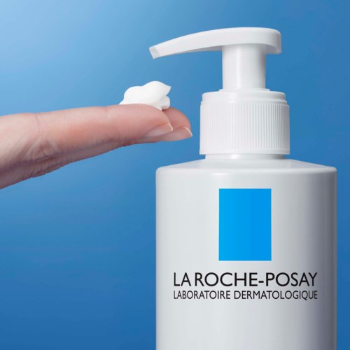 Een hand houdt een kleine hoeveelheid witte crème naast een witte pompflacon van La Roche-Posay.