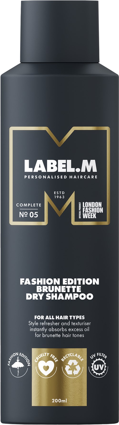 En mörkgrå flaska med vit och guld text, märkt som en fashion edition brunette torrschampo för alla hårtyper.