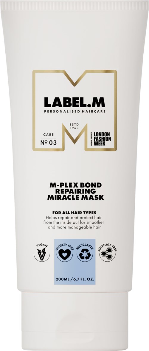 Vit hårmaskrör med svart och guld text, nämner reparation, vård och London Fashion Week.