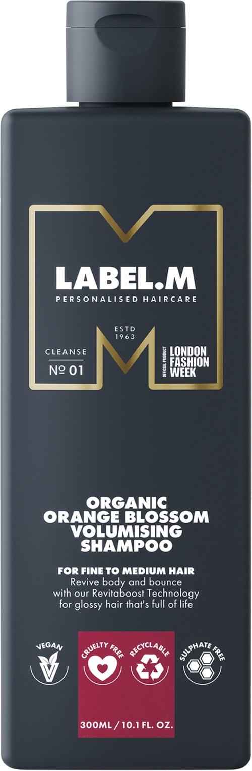 En mörk flaska med Label.M-schampo med guldig och vit etikett för organisk apelsinblomman volymgivande hår.