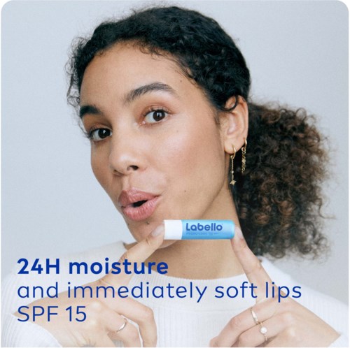 Een vrouw promoot Lipello lippenbalsem met 24 uur hydratatie, zachte lippen en SPF 15.