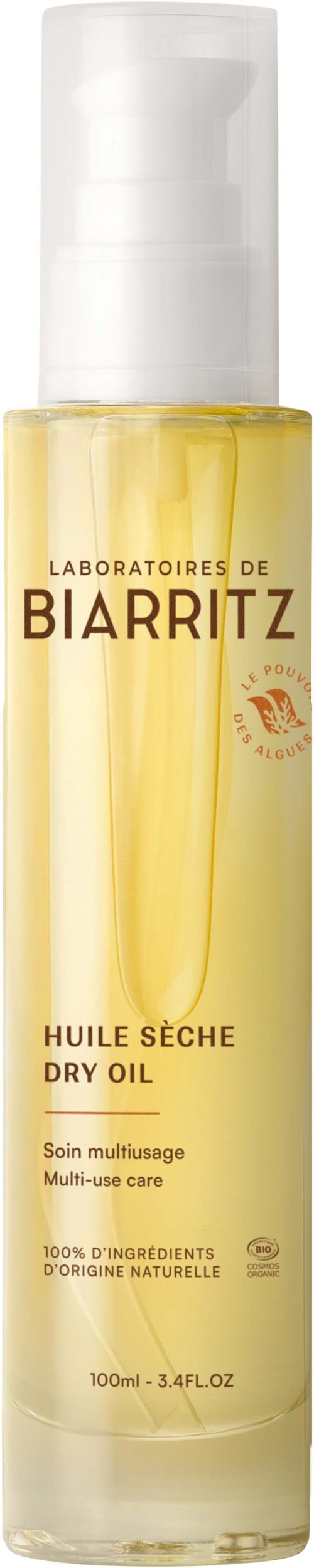 Een doorzichtige fles met witte pomp, gele vloeistof, tekst over droge olie van Biarritz Laboratories.