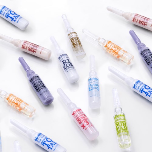 Verschiedene kleine Flaschen mit Tätowierungsfarbe oder Pigment in verschiedenen Farben verstreut auf einer weißen Oberfläche.