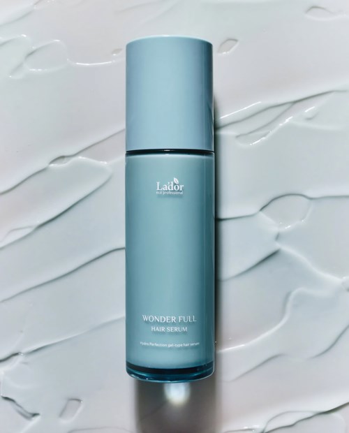 En lys blå flaske merket 'Wonder Full Hair Serum' på en hvit teksturert bakgrunn.