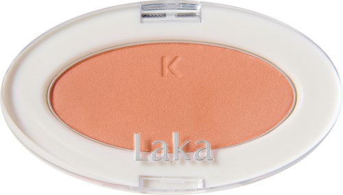 Een perzikkleurige make-up compact met een witte ovalen deksel, met een koraalroze blush binnenin, gelabeld "Laka."