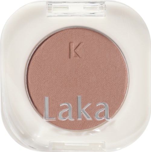 A round pressed powder with the brand name "Laka" on a white case. The powder is light brown.