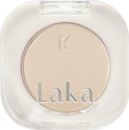 A round pressed powder compact with a light beige shade and the words "Laka" on it.