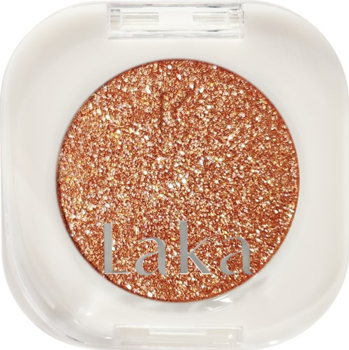A round, glittery, bronze-colored eyeshadow with the brand name Laka on it inside a white container.