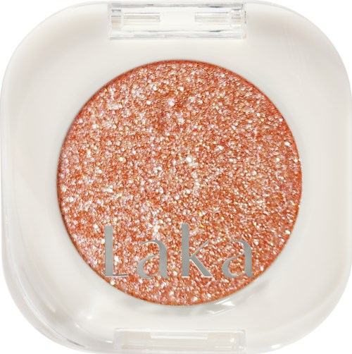 A round, shimmery, golden-pink eyeshadow in a white compact case with the name 'Laka' on it.