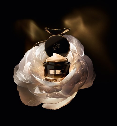 Ein kleiner Cremetiegel mit goldener Deckel steht in einer großen weißen Blume vor schwarzem Hintergrund.