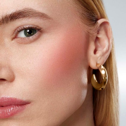Close-up of a woman's face showing her eye, cheek, ear, and a gold hoop earring.