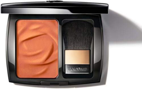 A makeup compact with orange blush and a black brush inside. The packaging is black and sleek.