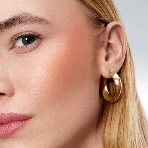 Close-up of a woman's face, showing her eye, part of her cheek, and a gold hoop earring.