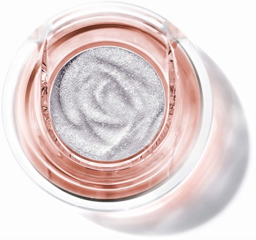 A round silver filter with a rose gold rim inside a transparent glass container.