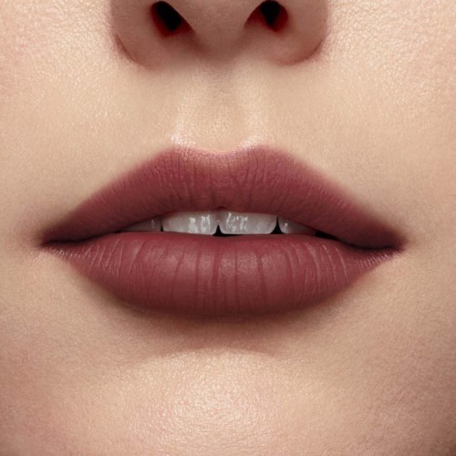 Close-up of lips slightly parted, showing teeth, with smooth skin and subtle makeup.