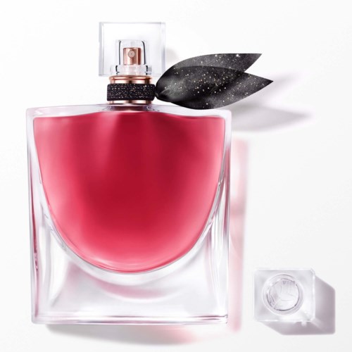 Een parfumfles met roze vloeistof, een spraydop, een zwart blad en een doorzichtige dop ernaast.