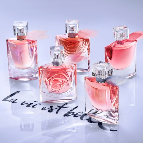 A collection of five pink perfume bottles with clear caps arranged on a light surface.