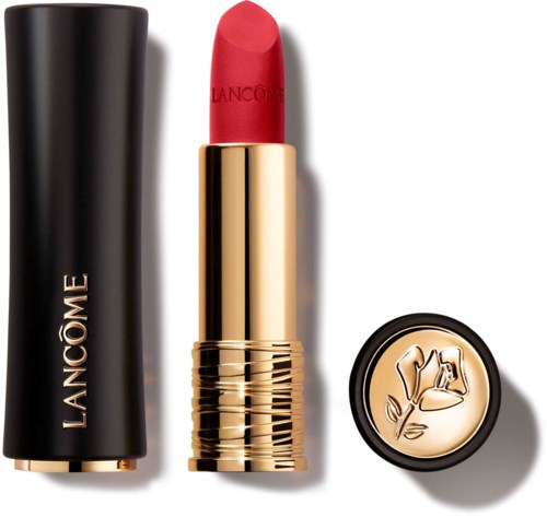 A red lipstick with a gold case, placed next to a black cap and a small round container.