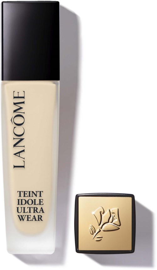 Lancôme foundationfles en compacte met logo op top. Eenvoudige, elegante verpakking met zwarte dop en beige vloeistof.