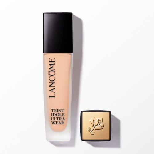 A bottle of Lancôme foundation with cap and a square gold lid featuring an embossed design.