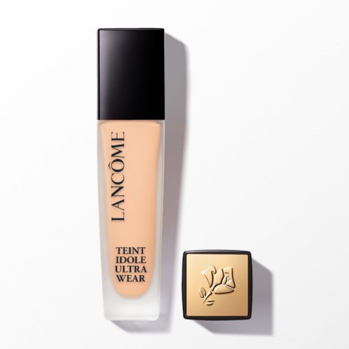 A bottle of Lancôme liquid foundation and a gold compact case with a logo. Clean, minimal background.