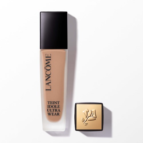 A bottle of Lancôme foundation with a black cap and a separate golden compact with an embossed logo.