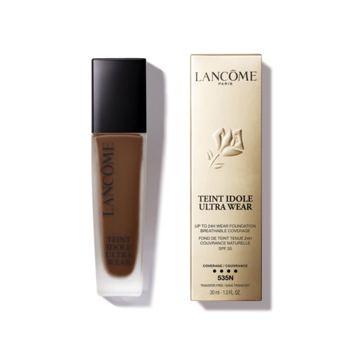 A bottle of Lancome foundation next to its box, in a brown shade with black cap.