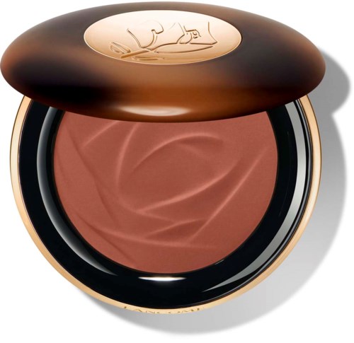 En rund kompakt med blush i en brun beholder, og et gullfarget lokk med inngravert logo.