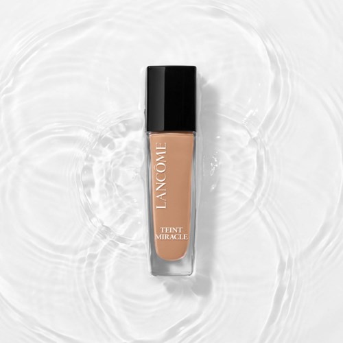 A beige liquid foundation in a clear bottle with black cap, labeled "Lanc 4me Teint Miracle."