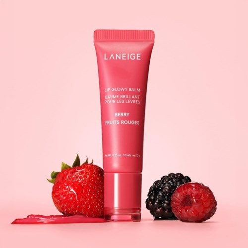 Lippenbalsemtube met aardbeien, framboos en bramen eromheen op roze achtergrond.