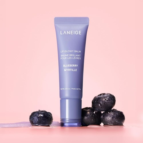 Een paarse Laneige lippenbalsem tube met de tekst "Blueberry Myrtille" omgeven door blauwe bessen op een roze achtergrond.