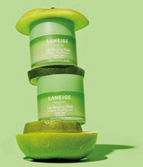 Opgestapte appelpartjes met groene Laneige Lip Sleeping Mask- containers ertussenin. Lichtgroene achtergrond.