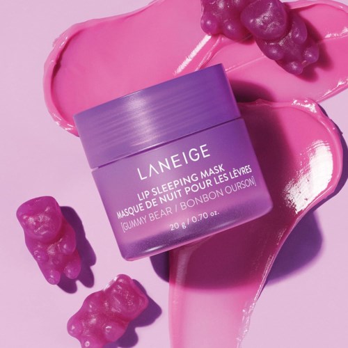 Lila lip sleeping mask pot omgeven door roze en paarse gummy beer snoepjes en roze lippenstiftvlekken.