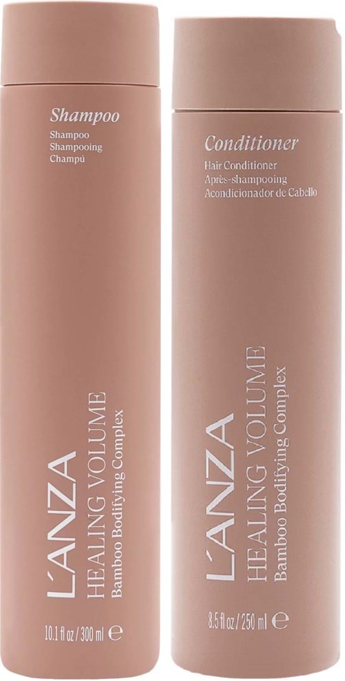 Kaksi vaaleanpunaisia pulloja, jotka on merkitty shampoolla ja hoitoaineella, seisovat vierekkäin. Ne ovat L'ANZA Healing Volume -sarjasta häämykseen.