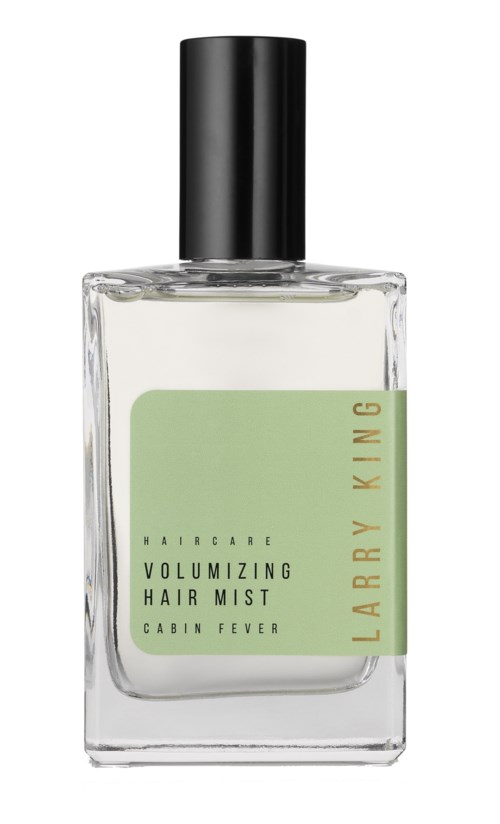 Eine klare Glasflasche mit schwarzem Deckel, beschriftet als Larry King Haarspray, grüne Etikette, Text zu Haarpflege und cabin fever.