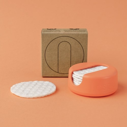 Eine Packung Wattepads, ein Pad außerhalb, pfirsichfarbener Behälter, einfarber Pfirsichhintergrund.